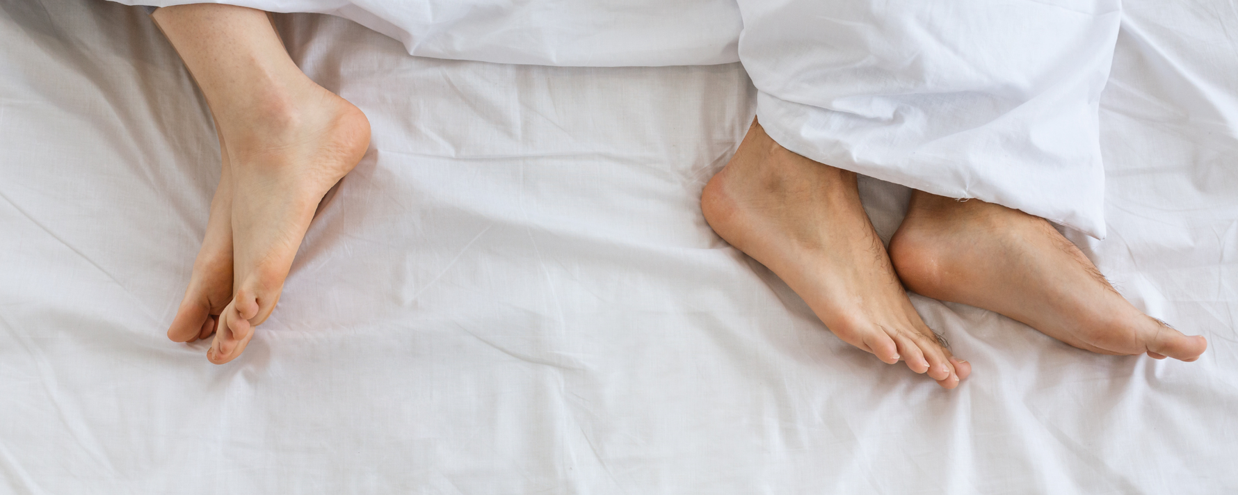 Ein paar im Bett von denen die Füße zu sehen sind