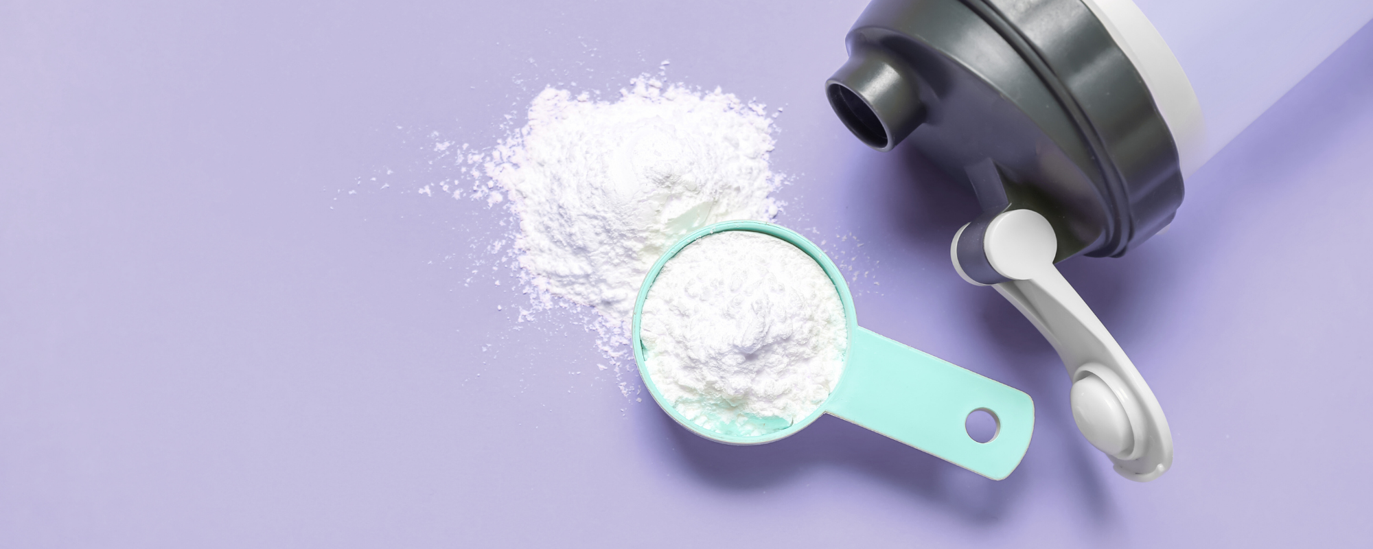 Kreatinpulver auf lila Hintergrund mit einer Trinkflasche daneben