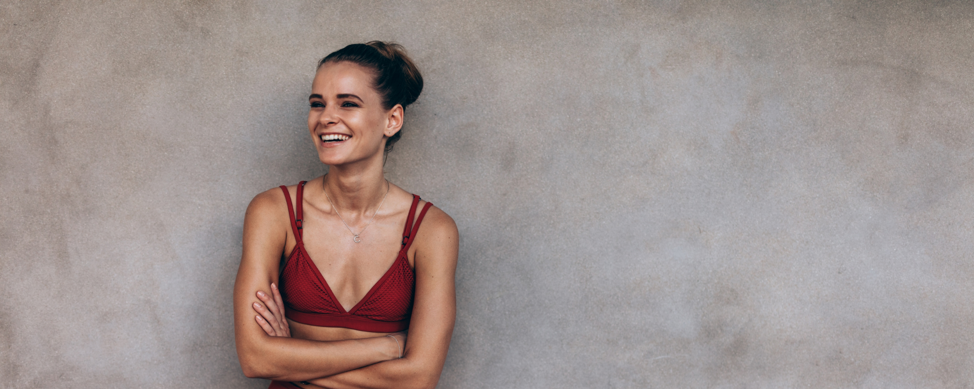 Sportliche Frau vor einer Wand, lachend und fröhlich