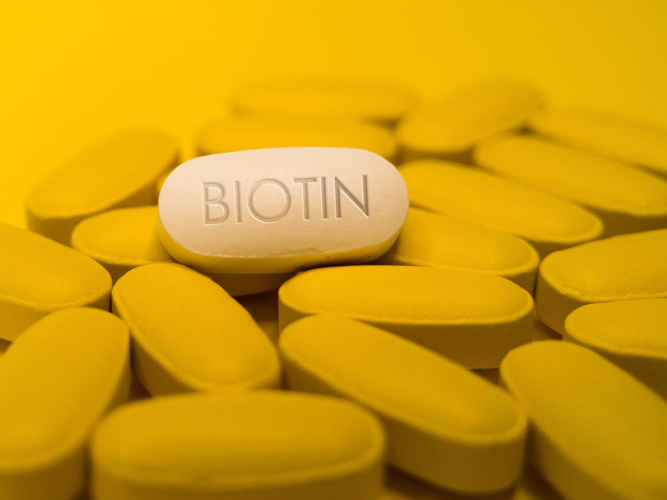 Biotinkapsel inmitten von gelben Kapseln